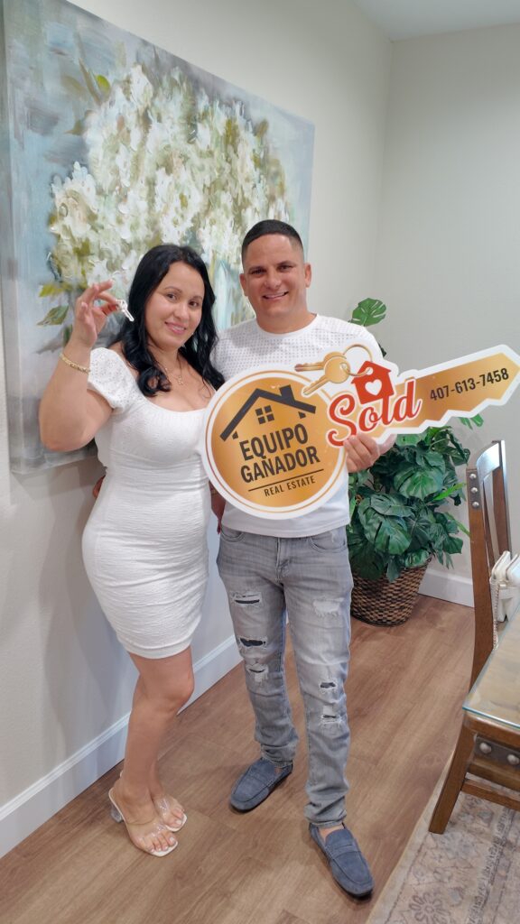 Pareja de clientes celebrando la compra de su casa con el cartel de vendido de Yailyn Homes